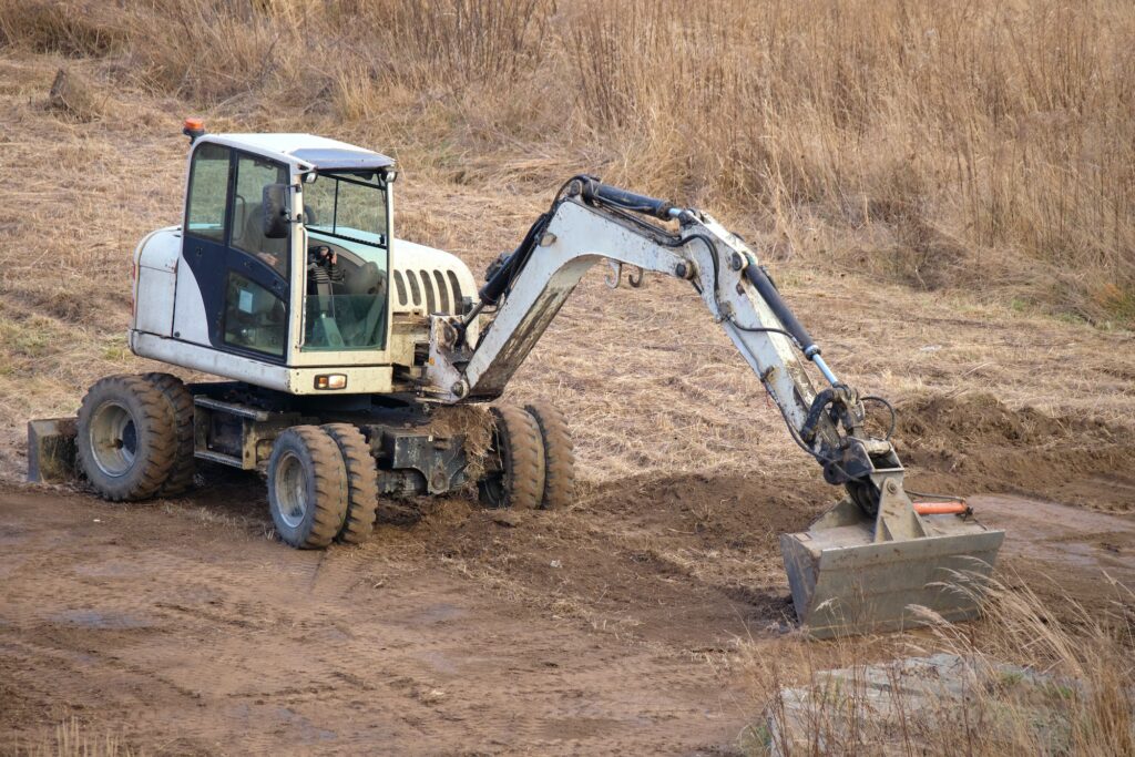 Earth moving tractor preparing place for future house foundation construction.